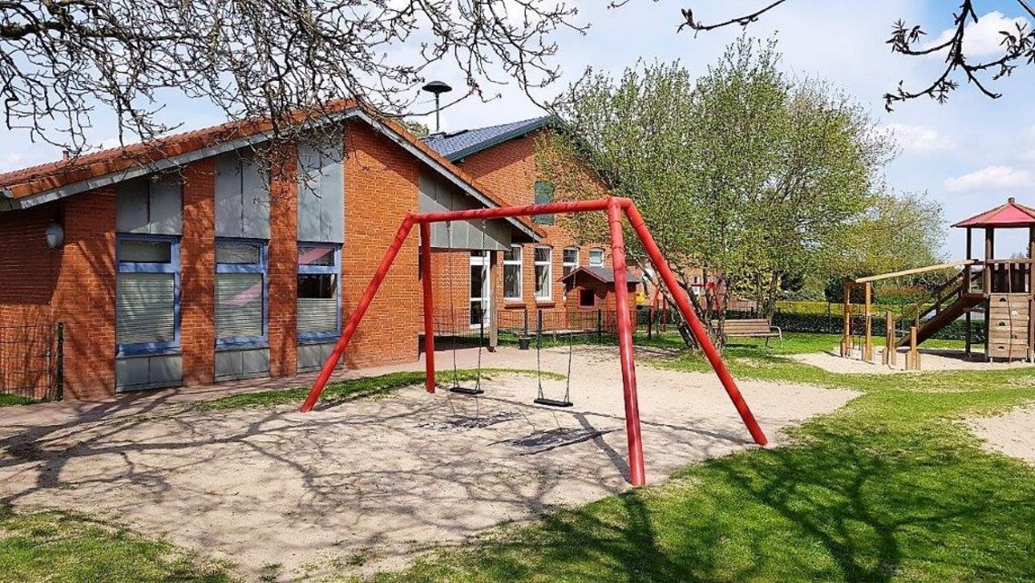 Im Vordergrund eine Schaukel, im Hintergrund ein Klettergerüst